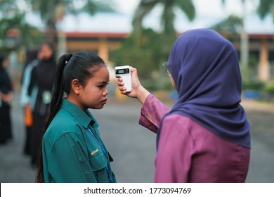 Muadzam Shah, Malaysia- July 9th, 2020:  Teacher Using Thermometer Temperature Screening Student For Fever Against The Spread Of COVID-19 While Student Coming Back To School, Education Concept.