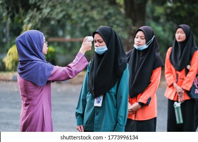 Muadzam Shah, Malaysia- July 9th, 2020:  Teacher Using Thermometer Temperature Screening Student For Fever Against The Spread Of COVID-19 While Student Coming Back To School, Education Concept.