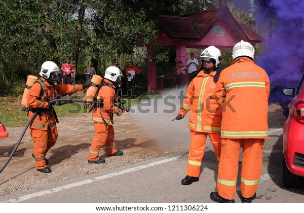 Muadzam Shah,Pahang-October 18th, 2018 :Fireman\
using water and extinguisher to fighting with fire flame in an\
emergency situation during road accidents in  Inter Agency Disaster\
Training Program 2018