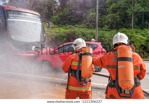 Muadzam Shah,Pahang-October 18th, 2018 :Fireman
using water and extinguisher to fighting with fire flame in an
emergency situation during road accidents in  Inter Agency Disaster
Training Program 2018