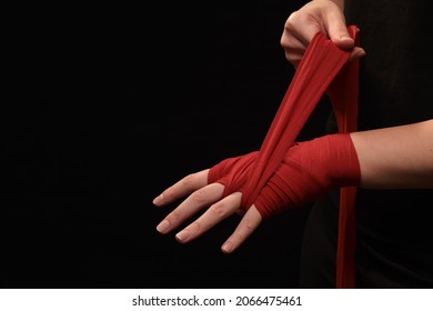 Muay Thai female boxer wearing strap on wrist closeup view. Fitness young woman preparing for boxing training on black background