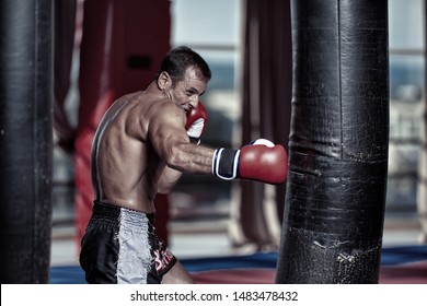 Muay thai fighter hitting the heavy bag in the gym - Powered by Shutterstock