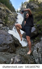 A muay thai or kickboxer training with shadow boxing by a strong waterfall