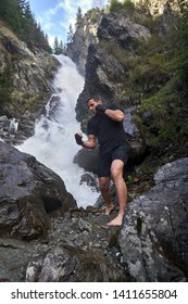 A muay thai or kickboxer training with shadow boxing by a strong waterfall