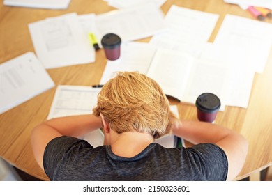 Too Much Coffee Can Lead To A Caffeine Crash. High Angle Shot Of An Exhausted Young Student Sleeping With His Head On A Cafe Table.