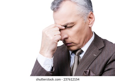 Too much problems. Frustrated mature man in formalwear touching head with fingers and keeping eyes closed while standing against white background