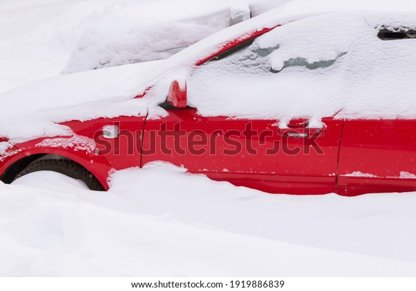 Much snow after snowfall and blizzard. Red car\
under snow in snowbank
