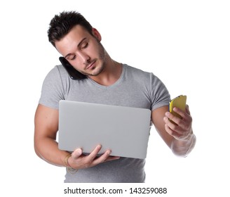 Too Much Technology. Young Man Using Two Mobile Phones And One Laptop Computer, Isolated On White