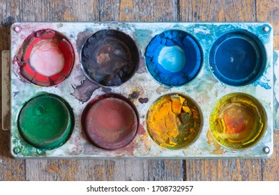 Much Used Plastic Watercolor Palette Box On Wood Background, With Messy Dry Cracked Paint