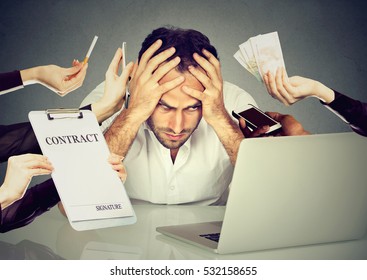 Too much work to do concept. Stressed young man sitting at his desk in front of computer in office. Busy schedule at workplace. Employee overwhelmed by errands should to be done