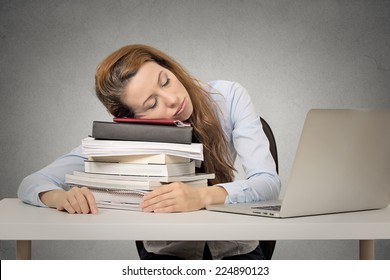 Too Much Work Tired Woman Sleeping On Books At Her Desk In Front Of Computer Isolated On Grey Wall Office Background. Busy Schedule In College, Workplace, Sleep Deprivation Concept 