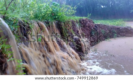 Mud and flowing water reach a pond / swamp during heavy rain looks like water fall causing soil erosion with wave and splash