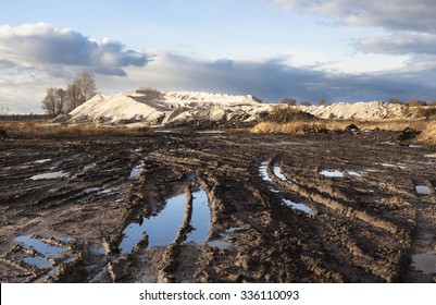 Mud And Puddles On The Dirt Road With Sand Hills In The Background.