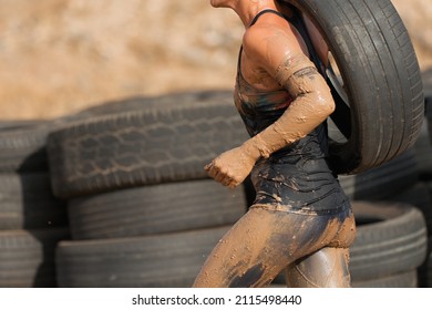 Mud race runner. Runner carrying tire in a test of the race