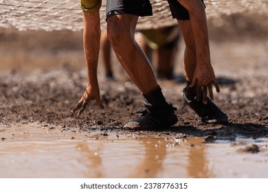 Mud race runners. Crawling, passing under a net obstacle during extreme obstacle race - Powered by Shutterstock