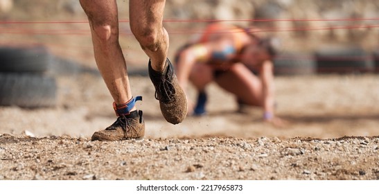 Mud race runners. Crawling,passing under a barbed wire obstacles during extreme obstacle race - Powered by Shutterstock