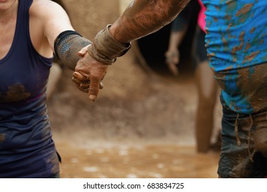 Mud race runners.The man helps the woman to overcome the obstacle - Shutterstock ID 683834725