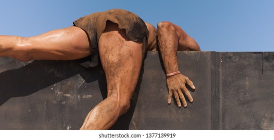 Mud Race Runners Running, Jump Over A Wall Obstacle