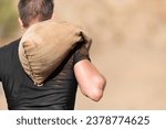 Mud race runners, young man carrying tear sandbag