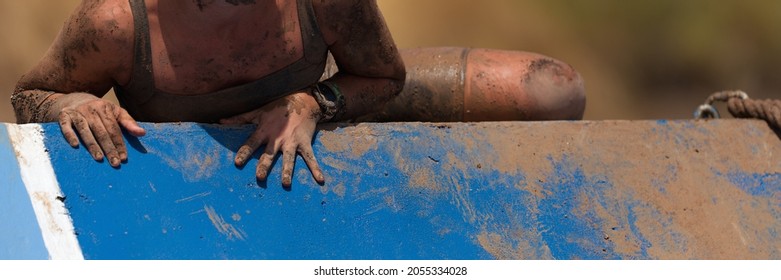 Mud Race Running. Running Over Obstacles Female Race Participant, Climbs Over Wall On Obstacle Course