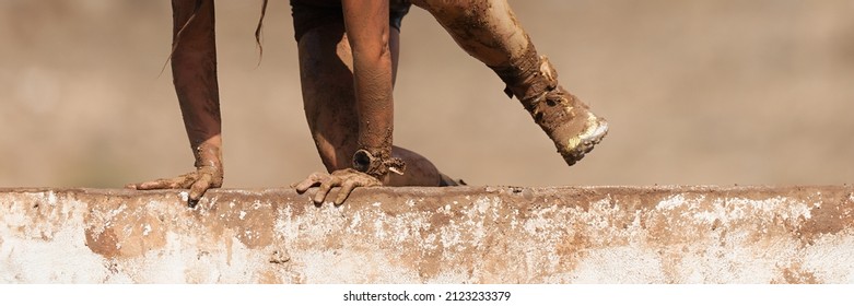 Mud Race Running. Running Over Obstacles Female Race Participant, Climbs Over Wall On Obstacle Course