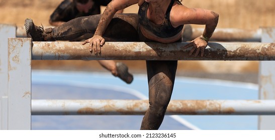 Mud race running. Running over obstacles female race participant, climbs over on obstacle course - Powered by Shutterstock