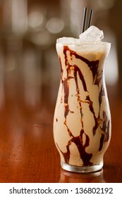 Mud Slide Cocktail Served On A Busy Out Of Focus Background With Chocolate Sauce In The Glass