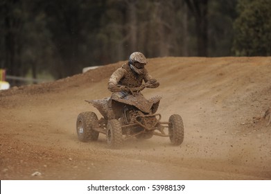 A Muddy ATV Racer Takes A Turn During A Race.