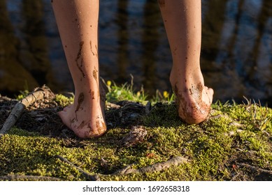 The Muddy Bare Feet Of A Little Boy While Standing On The Moss Edge Of A Creek While Getting Outside During The Coronavirus (covid-19) Pandemic. 