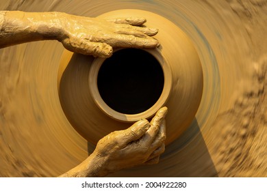 Muddy hands of a potter in focus while making a pot on a manual rotator. - Powered by Shutterstock