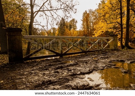 A muddy path around a pond with a wooden railing.