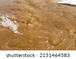 Muddy river water. Spring flood. Dirty muddy water with whirlpool and white foam close-up.