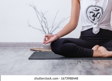 Mudra Gesture. Relaxed Harmonious Beautiful Brunette Woman Yoga Instructor Doing Lotus Position. Yogi Girl Sitting On Rug Floor During Workout. Copyspace. Cropp. Translate: Buddhism Symbol