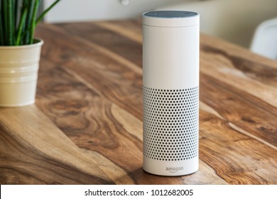 MUENSTER - JANUARY 27, 2018: White Amazon Echo Plus, Alexa Voice Service activated recognition system photographed on wooden table in living room, Packshot showing Amazon Logo