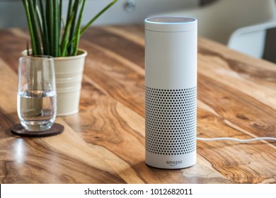 MUENSTER - JANUARY 27, 2018: White Amazon Echo Plus, Alexa Voice Service activated recognition system photographed on wooden table in living room, Packshot showing Amazon Logo