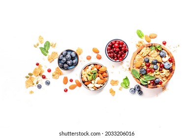 Muesli Bowl And Organic Ingredients For Healthy Breakfast. Granola, Nuts, Blueberry, Cranberry, Oatmeal, Greek Yoghurt, Whole Grain Flakes On White Table