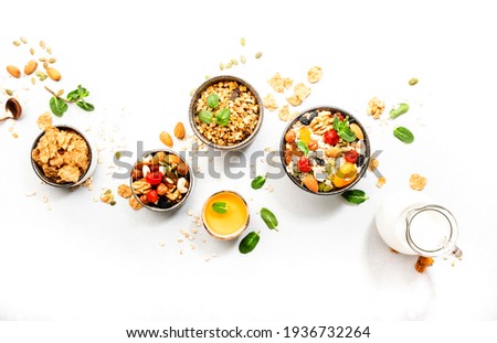 Muesli bowl, organic ingredients for healthy breakfast Granola, nuts, dried fruits, oatmeal, whole grain flakes on white background. Copy space, banner