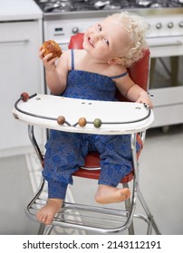 Muffin Love. A Sweet Little Baby Eating A Muffin While Sitting In Her High Chair.