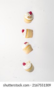 Muffins With Cream And Fresh Raspberries In Frozen Flight On A White Background. Minimalism. There Are No People In The Photo. There Is Free Space To Insert. Birthday, Holiday.