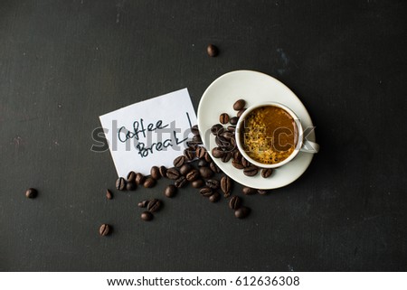 Mug with black coffee, coffee beans, milk and sugar on dark wooden table