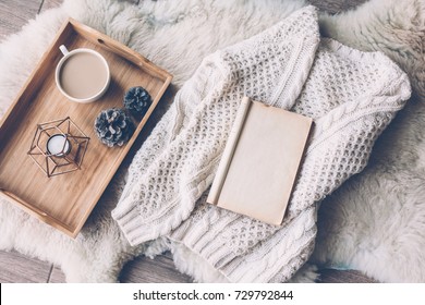 Mug With Coffee And Home Decor On Wooden Serving Tray On Sheep Skin Rug. Warm Sweater And Open Book, Winter Weekend Concept, Top View 