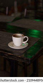 A Mug Of Coffee Stands On A Tray In A Restaurant.  Dark Colors, Loft Style Interior.  No People