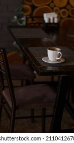 A Mug Of Coffee Stands On A Tray In A Restaurant.  Dark Colors, Loft Style Interior.  No People