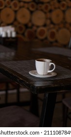 A Mug Of Coffee Stands On A Tray In A Restaurant.  Dark Colors, Loft Style Interior.  No People