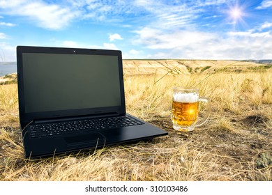 Mug of cold beer and laptop