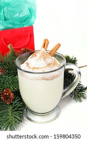 Mug Of Delicious Holiday Egg Nog On White Background With Pine Boughs And A Christmas Gift.  