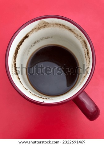 mug of drunk coffee with grounds on the bottom on a pink background