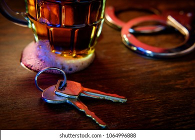 Mug of frothy beer with handcuffs and keys symbolizing drunk driving arrest - Shutterstock ID 1064996888