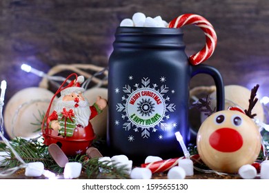 Mug of hot coffee with milk, marshmallow and Lollipop against rustic wooden background with Christmas decorations and lights. - Shutterstock ID 1595655130