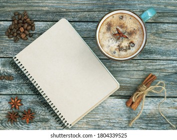 Mug Of Spice Latter Coffee, Winter And Autumn Hot Drink On Wooden Background. Blank Craft Notebook With Cup Of Coffee, Anise, Cinnamon, Beans Of Coffee. Flat Lay. Fall Mockup